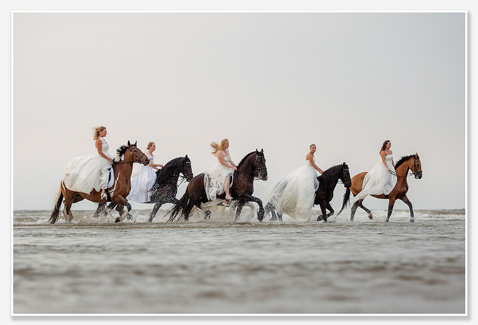 Bruiden te paard op het strand van Noordwijk