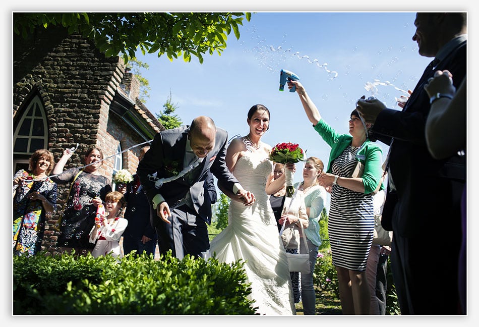Bruidspaar verlaat de trouwceremonie onder bellenblaas en serpentines