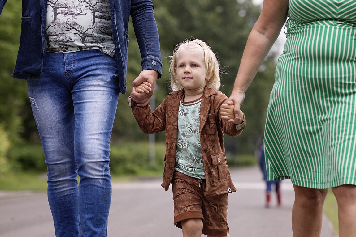 jongen bij vader en moeder aan de hand