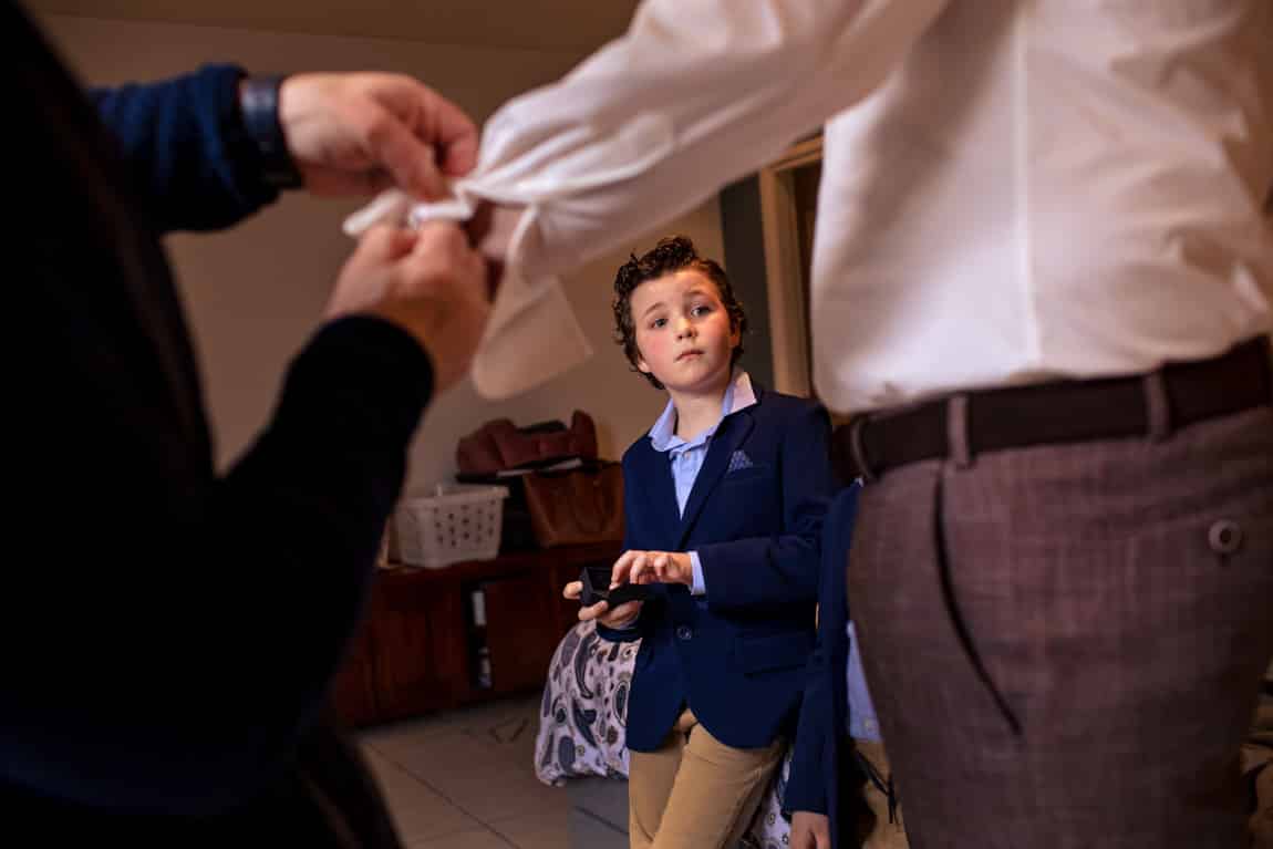 Bruidjonker kijkt toe bij aankleden bruidegom