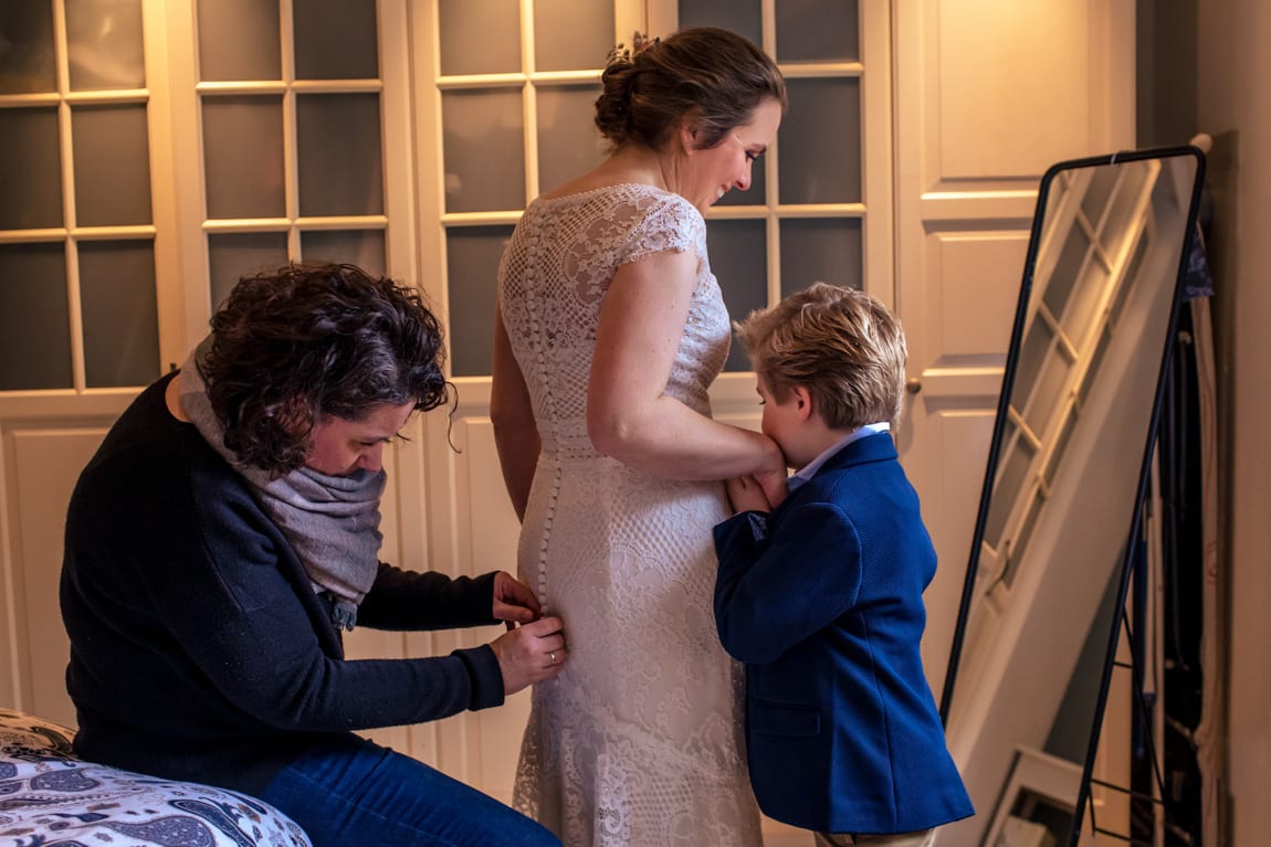 Aankleden van de bruid met bruidsjonker door Trouwfotografie Alblasserdam