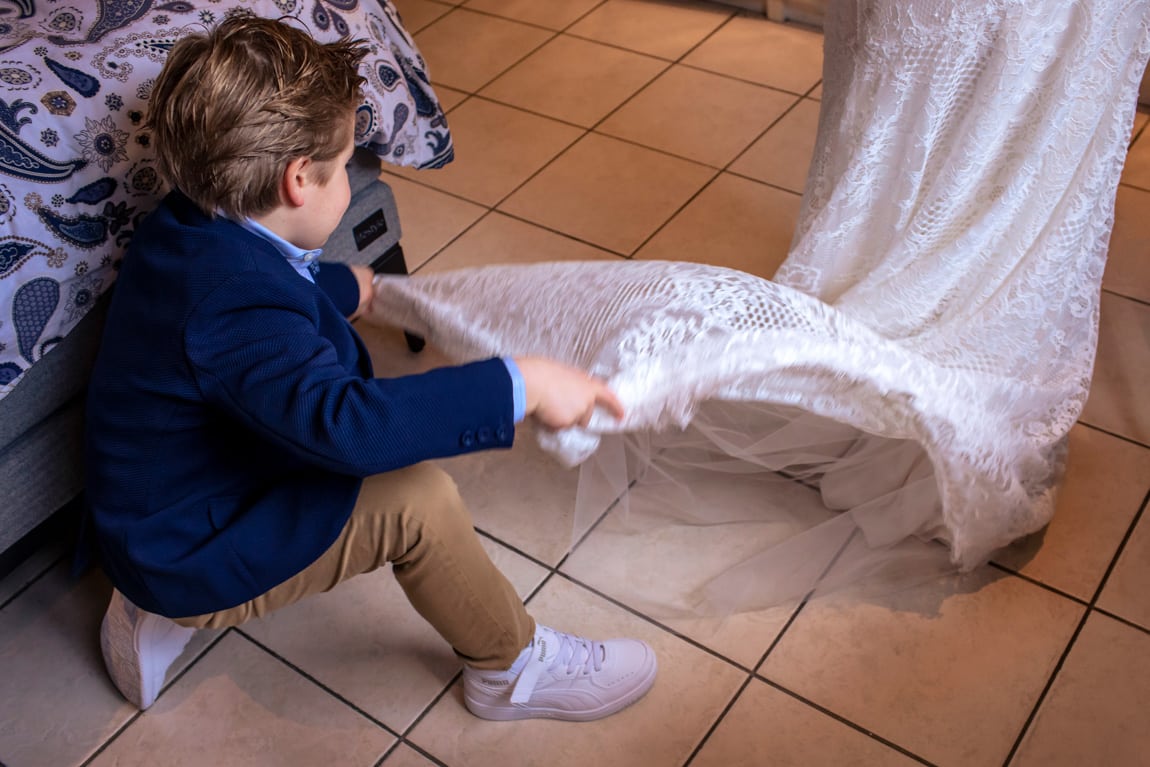 Bruidsjonker is doll op de trouwjurk