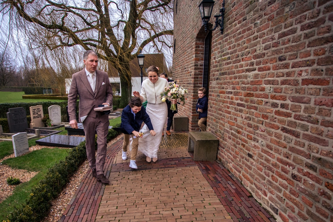 Bruidspaar verlaat keifhoekkerk bij sterke wind
