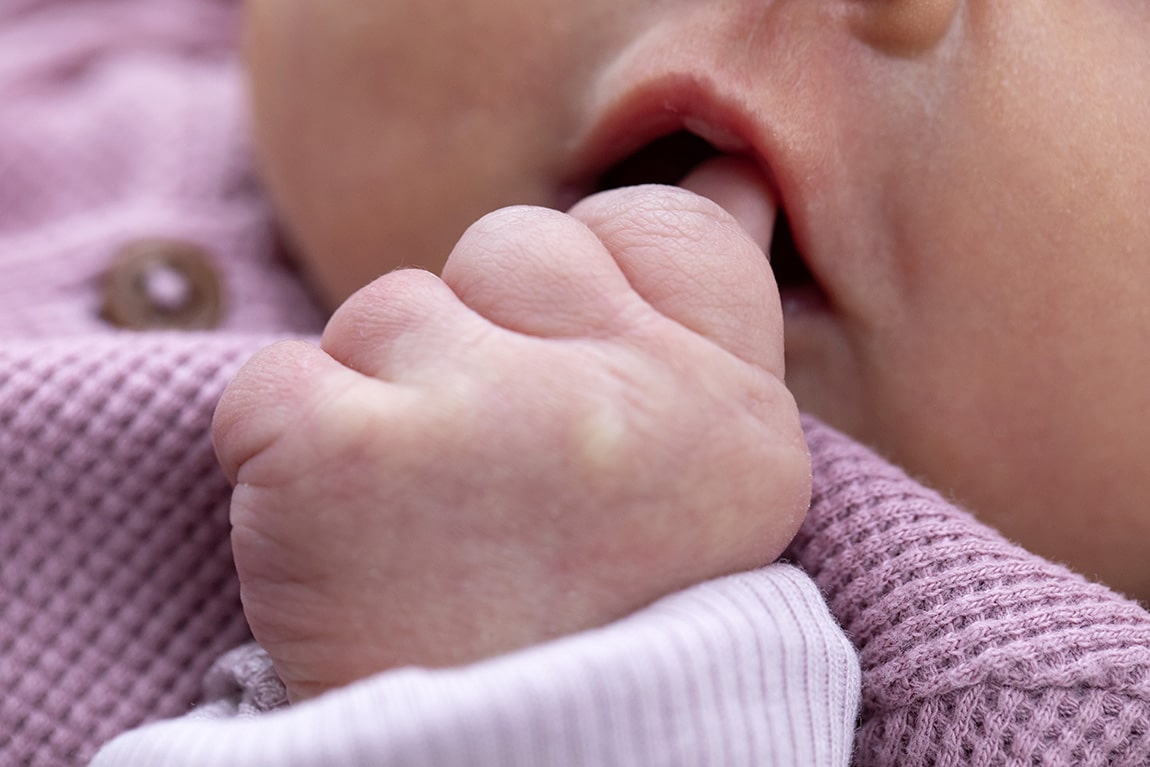 Newborn baby aan het duimen