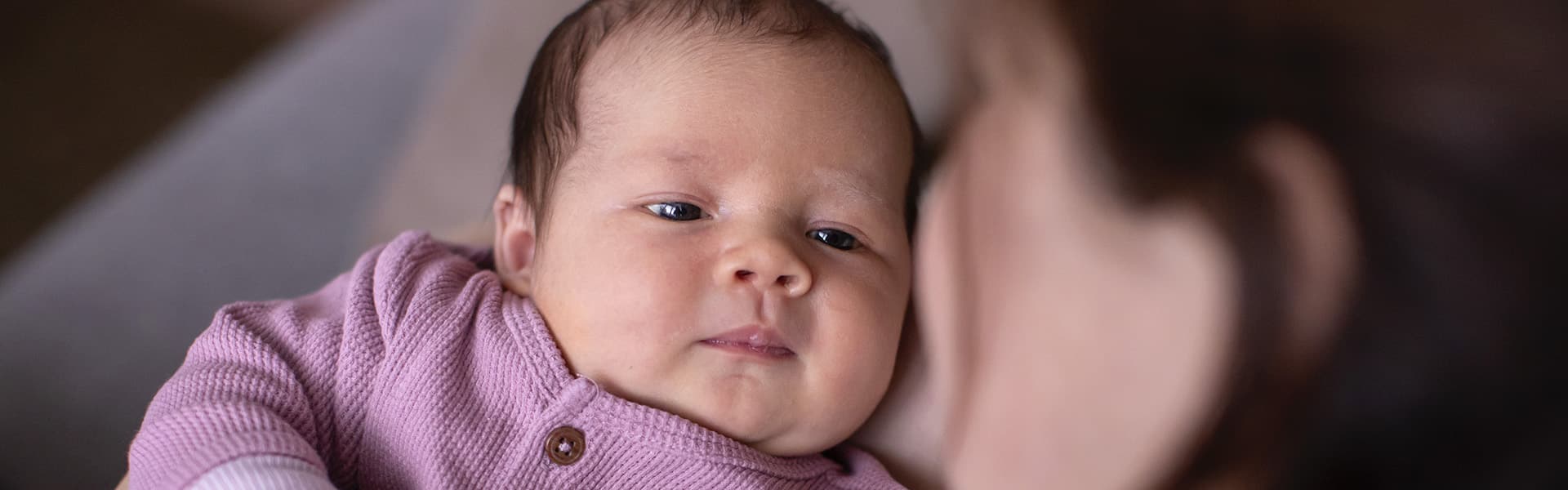 Baby kijkt moeder aan tijdens newbornreportage