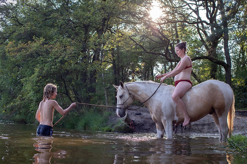 Moeder-zoon-moment bij het zwemmen met paarden