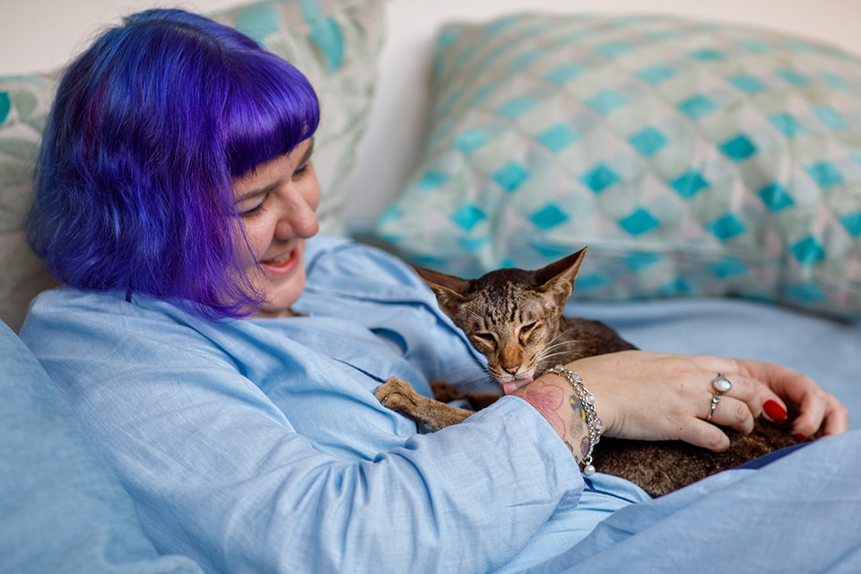 Kat likt hand van vrouwtje die lachend toekijkt