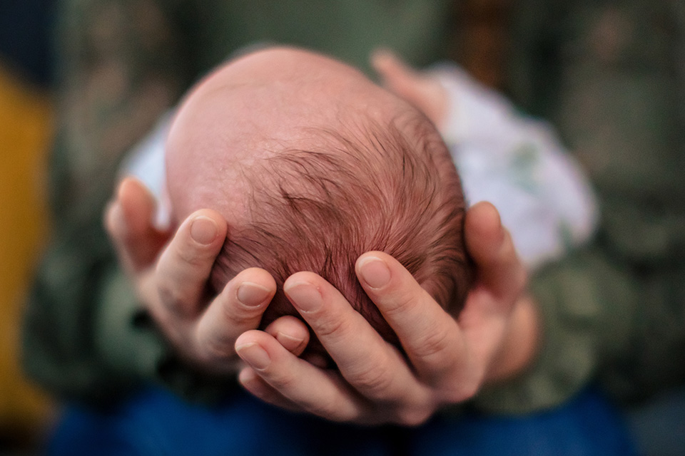 Moeder houdt hoofd van haar baby liefdevol in haar handen. Het heeft al veel haar.